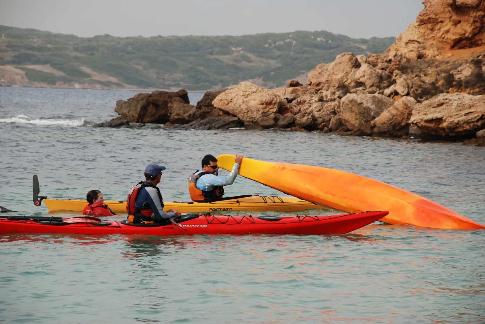 Participants practicant una maniobra de rescat amb caiacs de mar vora la costa