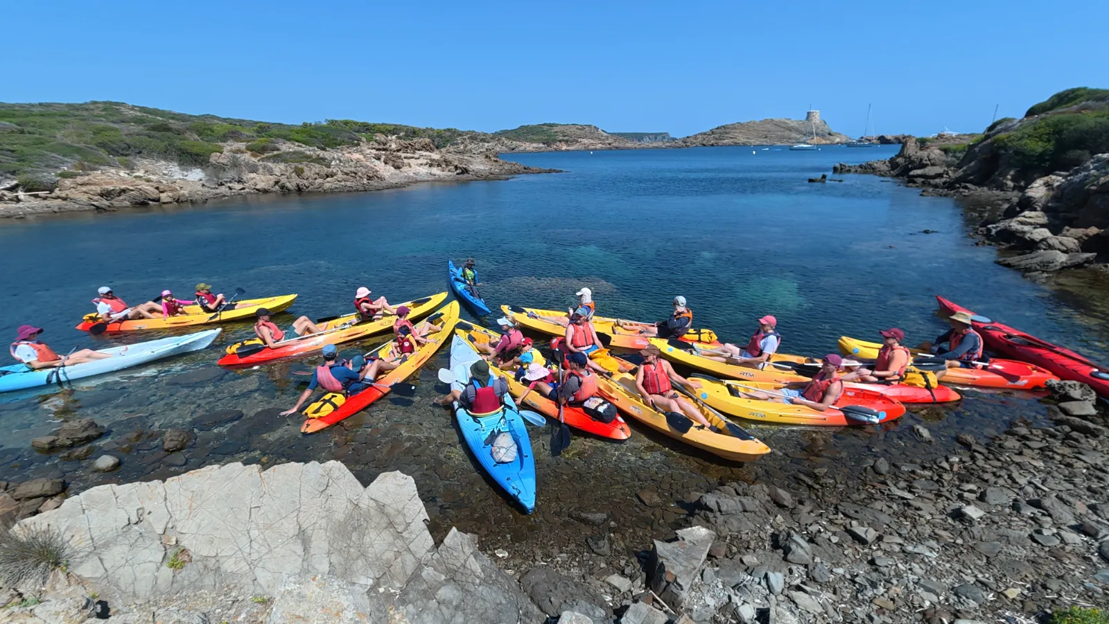Groupe de kayakistes réuni au bord d’une crique de Menorca